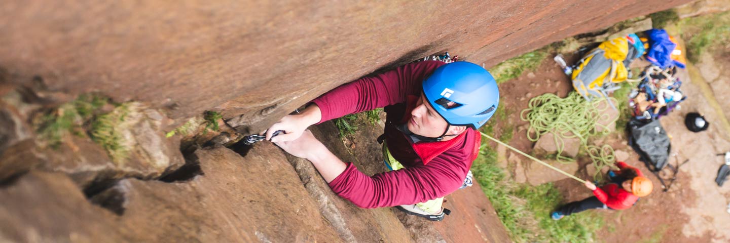 trad climber placing gear in a crack